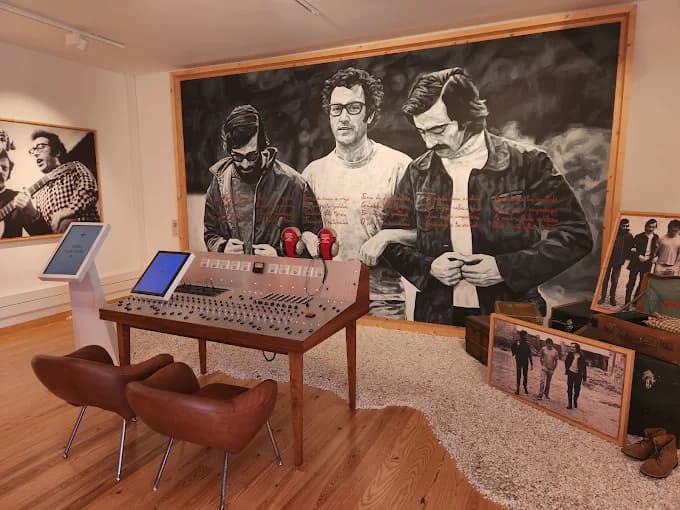 The installation in the museum: a touchscreen kiosk beside a mixing desk under a mural of José Afonso